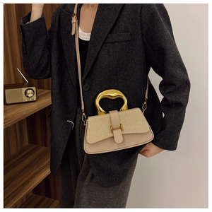 Detail of stylish beige box bag with woven texture lid and fluid gold metal handle