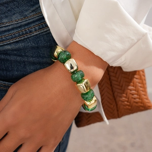 Detail of gold beads and green glitter acrylic spheres on a stylish beaded bracelet