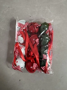 Detail of metal Christmas bells in red, white, and green with star cutouts and ribbons