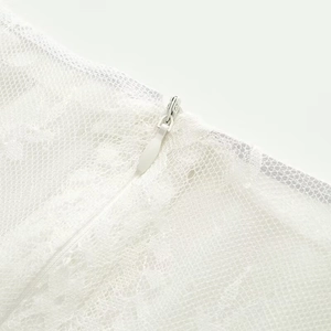 Dettaglio della trama in pizzo bianco e cerniera invisibile sull'abito estivo elegante