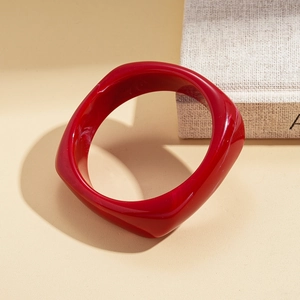 Detailed view of wide red resin bangle with glossy finish and unique rounded square shape