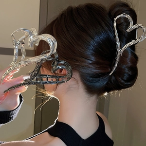 Vue détaillée d'une pince à cheveux argentée en forme de cœur sur des cheveux lisses