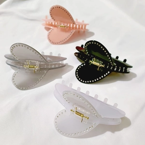 Dettaglio di quattro fermagli per capelli a cuore in rosa, grigio, nero e bianco con strass