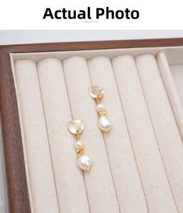 Close-up of golden brushed metal drop earrings with irregular white baroque pearls