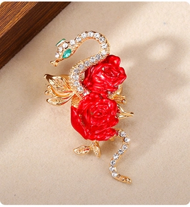 Macro detail of swan and red rose brooch with inlaid crystals on golden metal base