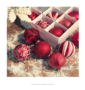 Detail of red Christmas baubles with various textures and glitters on snowy wood