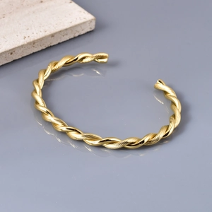 Macro detail of golden twisted rope cuff bracelet with smooth cylindrical end caps