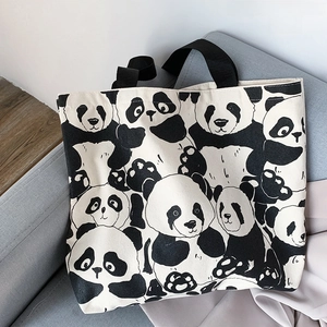 Close-up of cute panda print canvas tote bag with black handles on a soft gray sofa