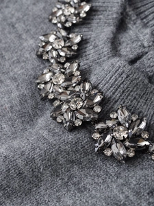Detailed close-up of crystal flower embellishments on grey ribbed knitwear fabric