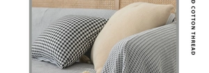 Detail of light gray textured cotton sofa cover with houndstooth and knit pillows