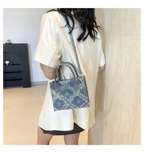 Detail of denim blue crossbody bag with star pattern, frayed edges, and adjustable strap