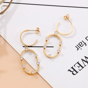 Détail de boucles d'oreilles créoles dorées avec strass blancs et pendentif ovale élégant