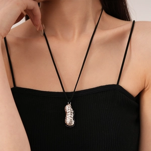 Detail of peanut-shaped silver pendant with textured finish on black cord necklace
