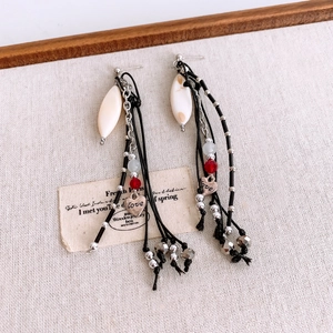 Macro detail of long beaded heart pendant earrings with vintage bohemian tassel design