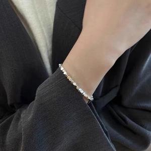 Close-up of minimalist faceted silver bead bracelet worn on a female wrist with a suit