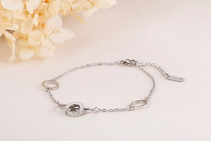 Detailed view of silver chain bracelet with interlocking rings and sparkling zircon accent