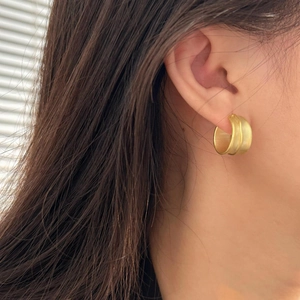 Close-up of minimalist gold matte hoop earrings shown on ear for size reference