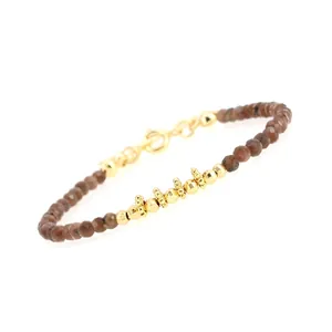 Detail of faceted brown stone beads and gold-plated accents on a delicate beaded bracelet