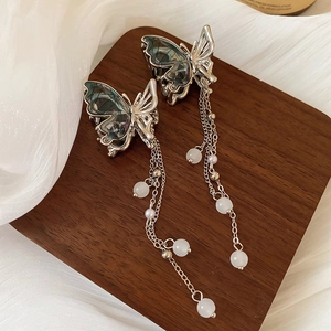 Détail de boucles d'oreilles papillon avec ailes dégradées vert foncé et pompons