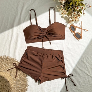 Flat lay of brown two-piece modest swimwear with side drawstring shorts and sunglasses