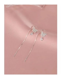 Detail of silver bow earrings with zircon stones and long tassels on pink silk fabric