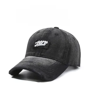 Detail of white aero embroidery on vintage washed black denim baseball cap with worn edges