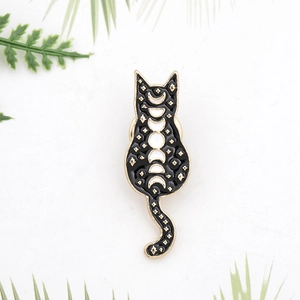 Detail of a black cat enamel brooch with lunar phases and golden stars on a white background
