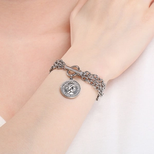Close-up of silver layered chain bracelet with OT toggle clasp and vintage coin pendant