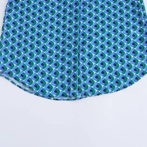 Détail de l'ourlet de la chemise avec motifs géométriques bleu et vert sur tissu