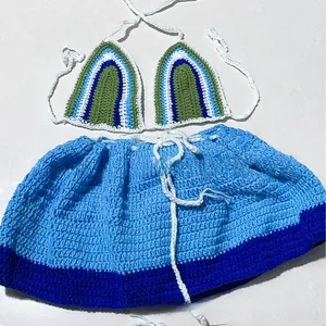 Close-up of handmade crochet bikini top and mini skirt in green and blue striped knit