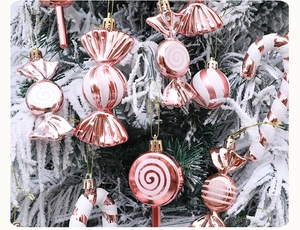 Close-up of pink and white candy-shaped ornaments on a snowy Christmas tree branch