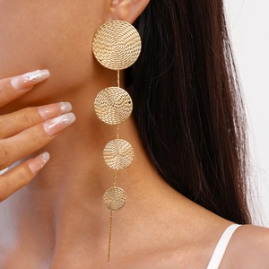 Close-up of elegant gold tiered circular drop earrings worn by a model on white background