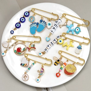 Golden safety pin set with colorful enamel charms like evil eye and lucky letters