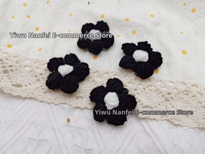 Detail of four handmade black and white crochet yarn flower patches for DIY crafts