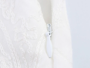 Detailed macro view of delicate white embroidery fabric with a hidden side zipper closure