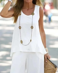Détail d'un haut d'été blanc sans manches avec un long collier à pendentif doré