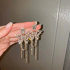 Détail de boucles d'oreilles papillon argentées avec glands et accents de perles