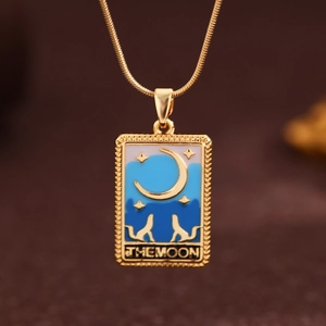 Macro shot of gold tarot pendant with blue enamel details and The Moon engraving