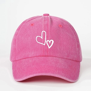 Pink washed denim baseball cap featuring two white heart prints on a minimalist background