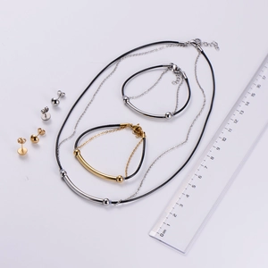 Close-up of gold and silver jewelry set with woven ropes and measurement ruler