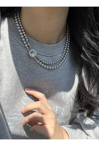 Detail of silver double-layered beaded necklace with square pavé clasp on a model