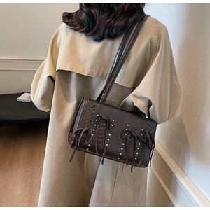 Detail view of dark brown PU leather shoulder bag with punk metal studs and bow tassels