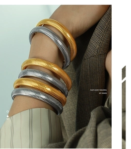Close-up of layered 10mm vintage textured snake-scale bangles in gold and silver