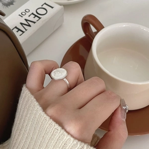 Close-up of a minimalist 925 silver shell cameo ring worn with cozy knitwear style