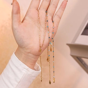 Detailed view of gold feather pendant necklaces with colorful pink and blue beads