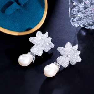Macro shot of silver zircon flower earrings with tear-drop pearls on a jewelry tray