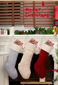 Close-up of cable knit Christmas stockings in grey, cream and red hung on a mantel