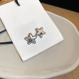Detailed shot of vintage silver star earrings with rustic finish on white card display