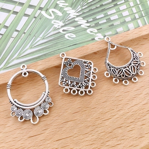 Close-up of vintage silver alloy jewelry connectors in heart and droplet shapes on wood
