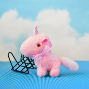 Nahaufnahme eines rosa Plüsch-Einhorns mit einer zarten violetten Schleife als Deko.